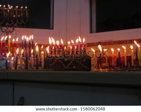 Chanukkah candles burning. candles made from Olive oil or wax (red in the picture). Hebrew text translation- these lights are sacred.