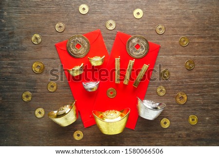 Top layout gold and silver bar and coins decorate on red envelopes with coins spread out on wood background,chinese new year concept.