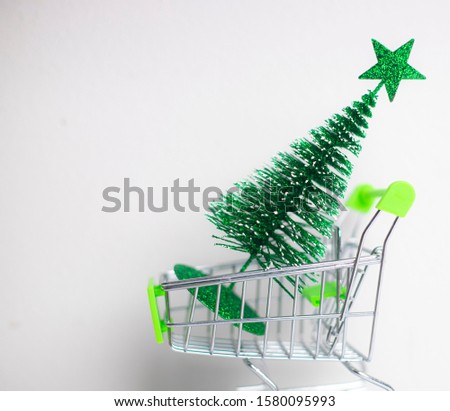 Green Christmas tree in the little shopping cart on the wood table and white background