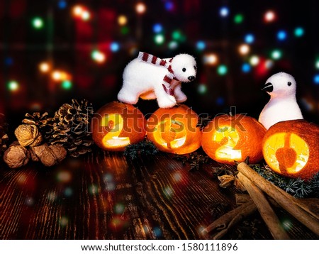 New Year picture. Toy white bear and penguin on the background of multi-colored lights of a garland with tangerine lights 2020.