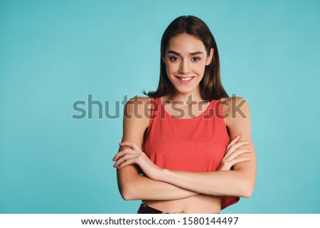Pretty smiling casual girl holding hands crossed confidently looking in camera over colorful background
