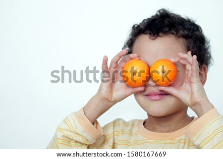 boy with orange fruit over his eye stock photo