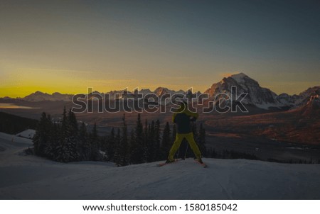 Skier preparing his poles and gloves in front of a majestic colorful early morning panorama of Lake Louise ski slope in Canada. Epic early skiing morning in Canada.
