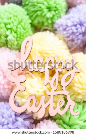 Happy Easter sign and pastel color pom poms on a pink background.