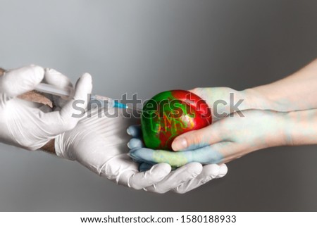 Man wearing medical gloves introduces a chemical into the fruit of the peach lying in the hands of women.Fruit and hands change color. Text. The concept of GMO foods