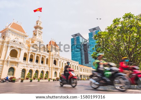 Downtown of Ho Chi Minh City, Vietnam: Saigon City Hall with waving Vietnamese flag, Vincom Center towers and colorful street traffic blurred in motion. Stock image with removed logos.