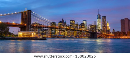 Panorama of Brooklyn Bridge, East River and Manhattan with lights and reflections. New York