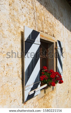Detail of the facade of the Predjama Castle. Windows with shutters decorated by beautiful red flowers on spot. Village Predjama, Slovenia.