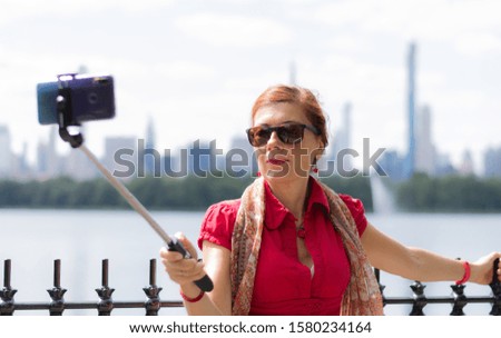 Woman taking a picture with mobile phone in a park, Central Park, New York