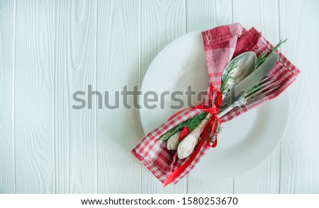 Christmas table with plate, cutlery. Christmas holiday background. Table setting for the holiday. Bright wood background. Space for text.