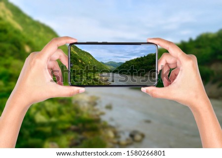 hand holding smartphone taking landscape image, mobile photography concept