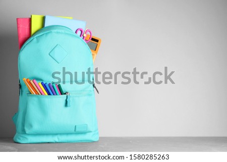 Stylish backpack with different school stationery on table against light grey background. Space for text Royalty-Free Stock Photo #1580285263