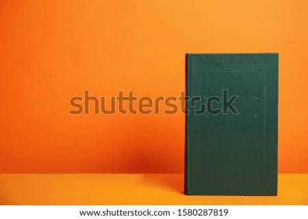 Hardcover book on orange background. Space for design