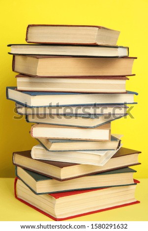 Stack of different hardcover books on yellow background