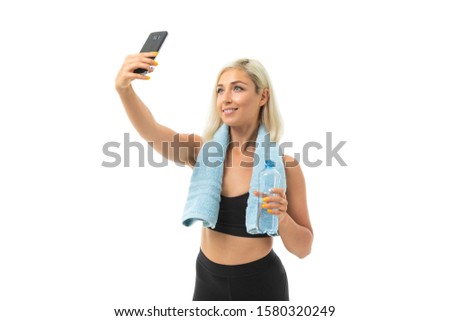 blonde girl in a sports uniform with a towel makes selfie on a white background