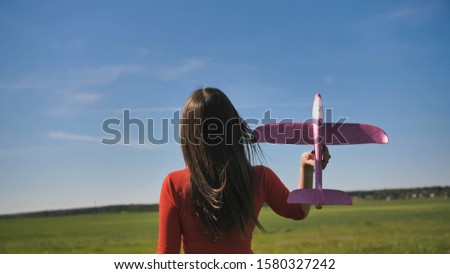 A girl launches a toy paralon airplane into the sky.