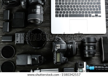 Flat lay composition with equipment for professional photographer on black wooden table