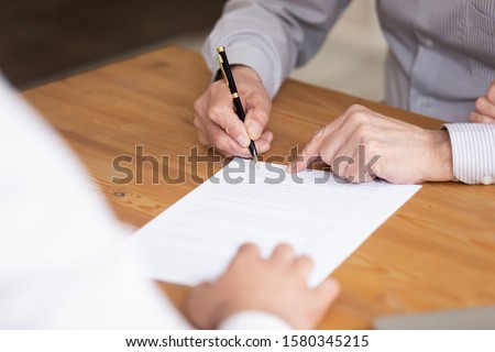 Close up elderly businessman hand holding pen put signature on business paper, man signing legal document making investment closing deal, taking bank loan or insurance, writing will testament concept Royalty-Free Stock Photo #1580345215