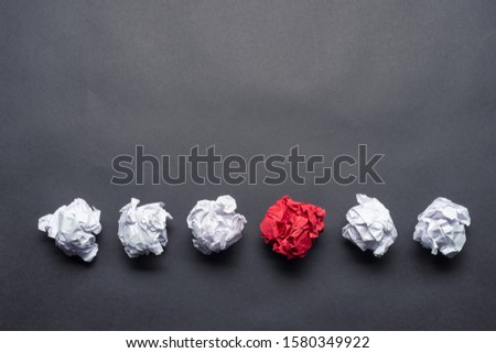 Crumpled red paper ball among white balls on black background. Extraordinary solution of problem. Think outside the box. Business motivation with copy space. Unique idea among failing ideas metaphor