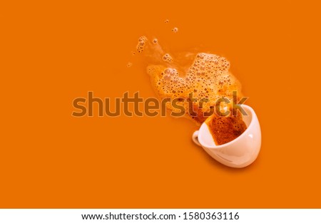 White cup of black coffee with foam on the orange background. Cappuccino background with smoke and one cup, copy space.