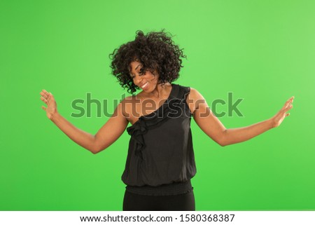 Lovely Black woman in a stylish top posing on greenscreen. Young woman dancing and having fun