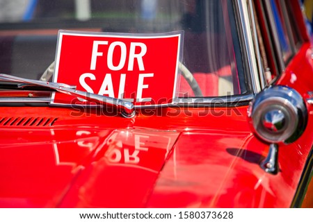 FOR SALE, red sign on classic antique American bright red car hood and chrome parts close up, during outdoor old cars show
