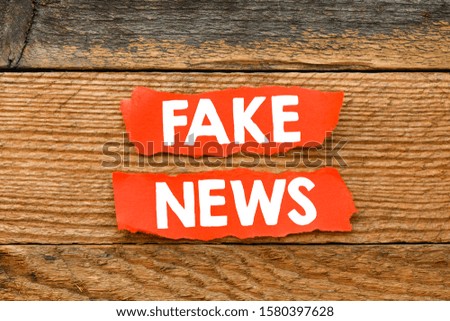 Fake News white text on red cards and wooden background. View from above. High resolution photography - business concept.