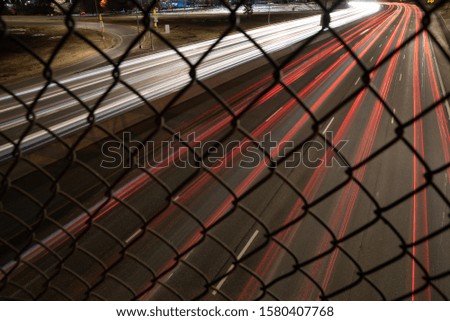 Light trails with wire fence pattern in the foreground