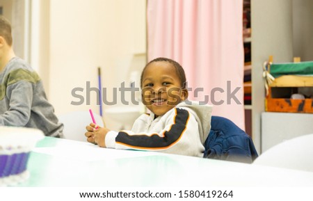 Portrait of smiling a little African boy in a school desk