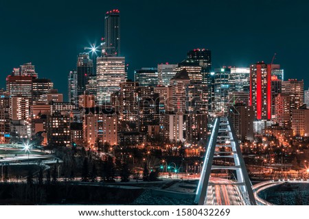 Long exposure of the Edmonton Alberta city skyline at night. The illuminated Walterdale bridge is in the foreground. Vehicle traffic is visible in the light streaks. Blue and Orange tones. Royalty-Free Stock Photo #1580432269
