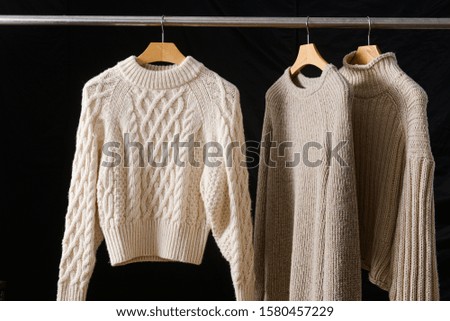 Set of three Knitted sweaters on hangers on black background


