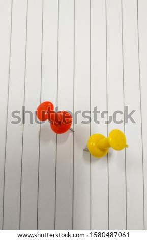 Red and yellow push pin isolated on a white paper