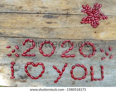 Happy New Year 2020, a symbol from the arrangement of red beans number 2020 on a wooden background.