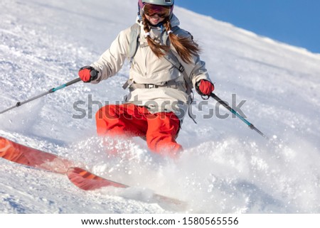 Girl On the Ski. Active winter holidays, skiing and snowboarding. Skier skiing downhill during sunny day in high mountains. Freerider on the ski track in the turn creates a snow wave and whirlwinds