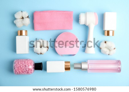Flat lay composition with face cleansing brushes on light blue background. Cosmetic tools