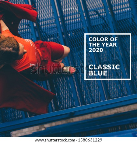 Color of the year 2020 Classic Blue. Young woman in red mantle posing on blue background. Millennial concept.