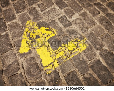 yellow painted right angled arrow on cobbled stone road