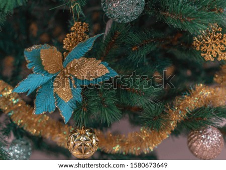 Close-up Christmas tree with Christmas decorations: golden xmas ball, snowflakes and big blue flower. Happy New Year concept.