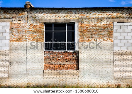old brickwork with traces of rebuilding, part of the modern old structure of the house with broken and bricked up Windows of different types of bricks and building materials, closeup