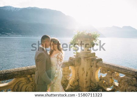 Bride in a beautiful wedding dress and groom are walking on a villa near the lake and mountains