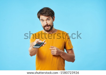 A cheerful man in a yellow T-shirt is a smartphone providing Internet services