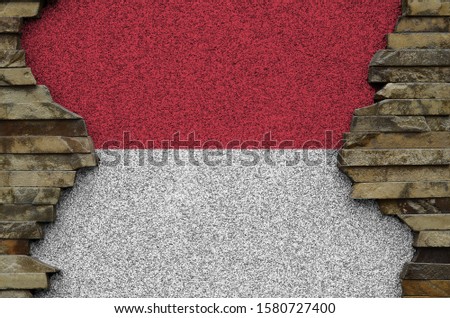 Monaco flag depicted in paint colors on old stone wall closeup. Textured banner on rock wall background