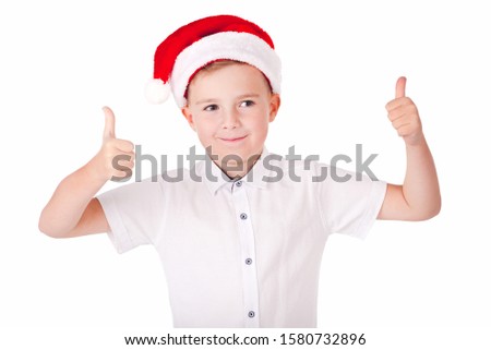 Attractive caucasian boy in Christmas hat. Wearing Santa hat, shows thumb up.Picture isolated.