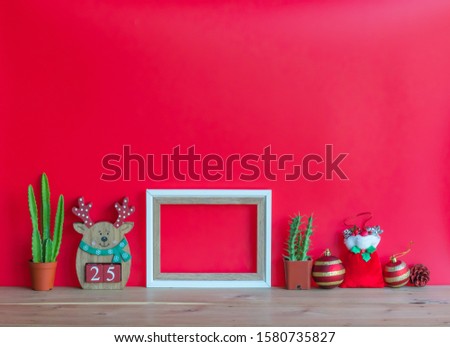 Christmas  creative  decorations,two  cactus,Santa  Claus,blank  wooden  picture  frame,balls,gift  and  pine  cone  on  wood  table  with  red  background