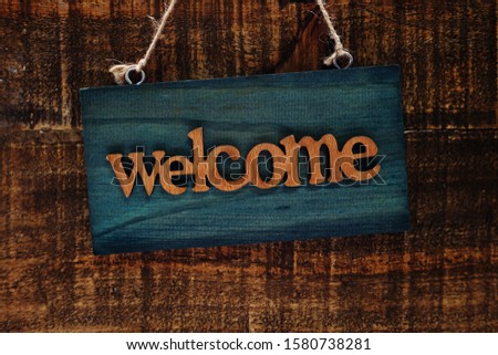 Wooden Welcome sign Hanging on space wooden background