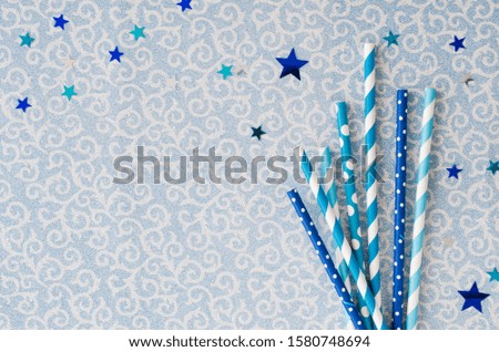 Eco friendly paper straws with various pattern in blue color for Christmas or New Year party. Shiny background with festive accessories for drinks. Christmas time concept. Top view or flat lay