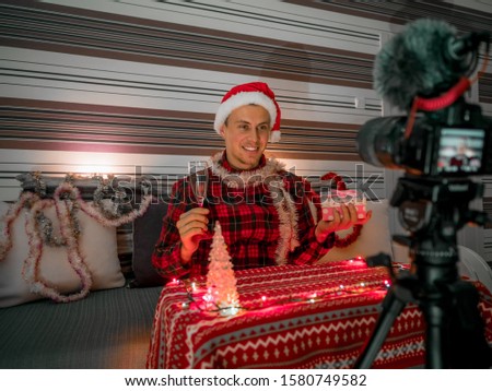 Smiling video blogger makes a Christmas video in room