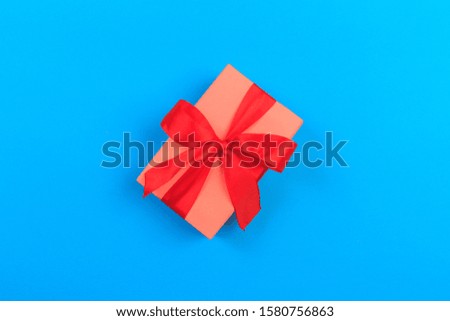 Gift box with ribbon and bow on color background and space for text. Top view