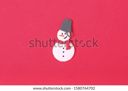 a handmade clay sculpture snowman wearing a red scarf and bucket hat on the red background