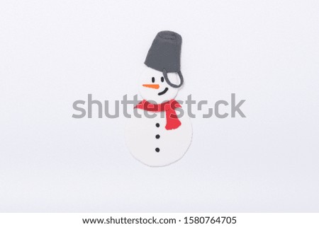 a handmade clay sculpture snowman wearing a red scarf and bucket hat on the white background